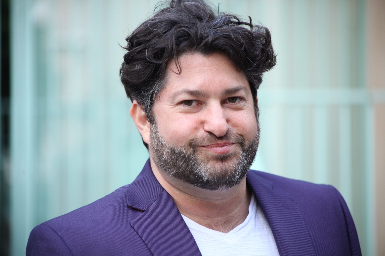 Commercial headshot of Ronan David in a purple jacket.