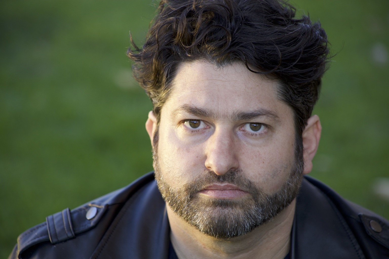 Theatrical headshot of Ronan David against a green background.